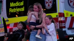 People are led out from the Westfield Shopping Centre, where multiple people were stabbed in Sydney, April 13, 2024. 