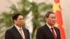 Vietnam's Prime Minister Pham Minh Chinh, left, and Chinese Premier Li Qiang listen to national anthems during a welcome ceremony in the Great Hall of the People in Beijing, June 26, 2023. (Pool photo via AP)
