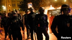 A group of police officers walk as people protest following the death of Nahel, a 17-year-old teenager killed by a French police officer in Nanterre during a traffic stop, and against police violence, in Paris, France, June 30, 2023. 