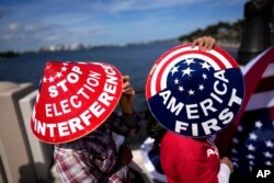 Members of a California group called Patriots for Freedom, who were in town to attend a fundraiser for Republican presidential candidate Donald Trump, wear hats showing their support outside his Mar-a-Lago estate, Feb. 16, 2024, in Palm Beach, Fla.