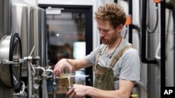 FILE - Brewer Scott Peterson measures out a sample of wort while brewing a German-style Pilsner at Von Ebert Brewing in Portland, Ore., Oct. 22, 2023. 