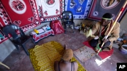 FILE - Traditional healer Shadrack Mashabane consults with his wife before testing her for HIV in Bushbuckridge, South Africa, May 9, 2024. 