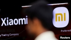FILE - A man walks past a logo of Xiaomi, a Chinese manufacturer of consumer electronics, outside a shop in Mumbai, India, May 11, 2022.