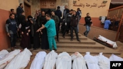The shrouded bodies of people killed in Israeli bombardment on Khan Yunis in the southern Gaza Strip, are laid out for identification by relatives, in front of the morgue of the Al-Nasr hospital on Nov. 19, 2023,