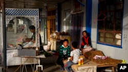 FILE - A Uyghur woman works while children play in Hotan, in western China's Xinjiang region, Sept 20, 2018. China faced international criticism about its human rights record, mainly on its treatment of Uyghurs, Thursday at a United Nations Human Rights Council session in Geneva.