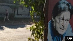 Seorang warga berjalan melewati poster mantan Perdana Menteri Pakistan Imran Khan yang terpasang di sebuah area di Islamabad, Pakistan, pada 23 Desember 2023. (Foto: AFP/Aamir Qureshi)