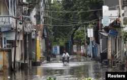 A man rides a motorcycle through a waterlogged street in Mandvi before the arrival of Cyclone Biparjoy in the western state of Gujarat, India, June 15, 2023.