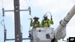 Workers repair a power line on June 29, 2023, in Houston. An unrelenting heat wave in Texas is testing the state's power grid as demand soars during a second week of triple-digit temperatures.