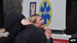 Local residents react outside a building damaged by a missile attack in Kyiv, Ukraine, Feb. 7, 2024.