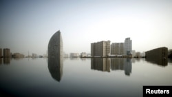 FILE - The skyline of Baku is reflected in the waters of an artificial waterfall near the Heydar Aliyev Center, Azerbaijan June 15, 2015. 