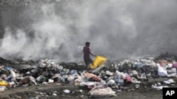 FILE - A woman walks through a landfill looking for salvageable items, in Port-au-Prince, Haiti, Saturday, July 1, 2023. (AP Photo/Odelyn Joseph)