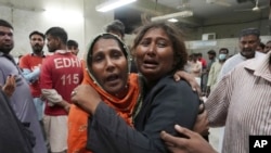 Women at a morgue in Karachi, Pakistan, mourn the loss of a family member who was killed in a stampede at a Ramadan food distribution center, March 31, 2023. 