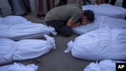 Palestinians mourn relatives killed in the Israeli bombardment of the Gaza Strip, in front of the morgue in Deir al Balah, Oct. 31, 2023.