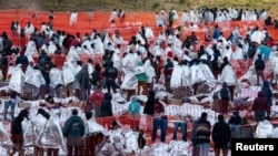 Migrants wear mylar blankets supplied by the U.S. Border Patrol to keep warm in the early hours of the morning after spending the night in an outdoor processing center in Eagle Pass, Texas, Dec. 20, 2023.