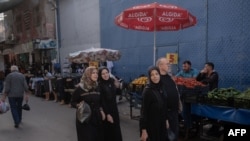 Syrian women walk in the Kocavezir neighborhood of Adana, in southern Turkey, which hosts a large number of Syrian refugees who fled the civil war, May 25, 2023.
