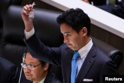 Pita Limjaroenrat, leader of the Move Forward Party, holds up his ID card at parliament after Thailand's Constitutional Court ordered his temporary suspension from the parliament, on the day of the second vote for a new prime minister, in Bangkok, July 19, 2023.