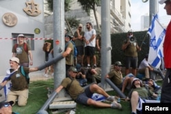 People chain themselves together in front of the Ministry of Defense on the 'Day of National Resistance' in protest against Israeli Prime Minister Benjamin Netanyahu's judicial overhaul, in Tel Aviv, July 18, 2023.