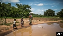 A family walks home after collecting food from a distribution organized by the World Food Program and World Vision in Simumbwe, Zambia, Jan. 22, 2020. Four years later, the country is experiencing a severe drought threatening national food security. 