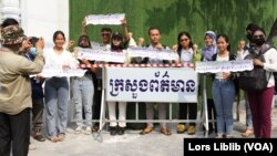 យុវជនមួយក្រុម លើកបដា នៅខាងមុខក្រសួងព័ត៌មាន ក្នុងរាជធានីភ្នំពេញ នៅពេលពួកគេដាក់ញត្តិស្នើសុំក្រសួងព័ត៌មានឱ្យបើកស្ថាប័នវីអូឌី និងសា្ថប័នសារព័ត៌មានឯករាជ្យផ្សេងឡើងវិញ កាលពីថ្ងៃទី៣១ ខែមីនា ឆ្នាំ២០២៣។ (លាស់ លីបលីប/វីអូអេ)