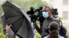 FILE - A news media cameraman is blocked with umbrellas by counter protesters at Freedom Plaza in Washington, Sept. 18, 2021, as they try to prevent coverage of a planned rally by supporters of former President Donald Trump.