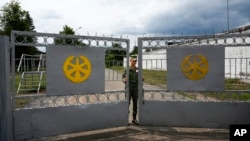 A Belarus army soldier closes the gate of the Belarusian army camp near Tsel village, about 90 kilometers southeast of Minsk, July 7, 2023.