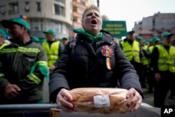 FILE - A woman holds a loaf of bread during a farmers' protest in front of the Representative Office of the European Commission in Bucharest, Romania, April 7, 2023.