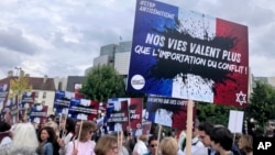People rally against antisemitism, one carrying a placard reading 'Our lives worth more that an imported conflict' June 20, 2024, in Paris. 