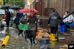 Pedestrians walk along a flooded sidewalk in the Brooklyn borough of New York, Sept. 29, 2023. The deluge shut down swaths of the subway system, flooded some streets and highways, and cut off access to at least one terminal at LaGuardia Airport. 