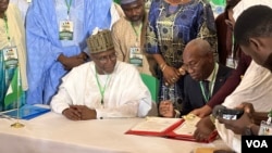 Nigeria's environment minister, Balarbe Abbas Lawal, seated at left, and his Cameroonian counterpart, Jules Doret Ndongo, are pictured at the signing of a transborder agreement to protect wildlife, in Abuja, Nigeria, April 19, 2024. (Timothy Obiezu/VOA)