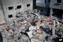 A Palestinian walks through the rubble of the Khatab family building after an Israeli airstrike in Deir al Balah, Gaza Strip, Feb. 21, 2024.