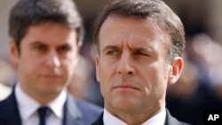 FILE - French President Emmanuel Macron and French Prime Minister Gabriel Attal, background, attend a ceremony in Paris, March 20, 2024. Following a snap legislative election, Macron has lost his parliamentary majority.
