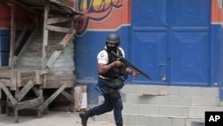 A police officer takes cover during an anti-gang operation in Port-au-Prince, Haiti, April 25, 2023, a day after a mob in the Haitian capital pulled 13 suspected gang members from police custody at a traffic stop and beat and burned them to death with gasoline-soaked tires.