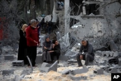 Palestinians sit on the rubble of a destroyed house following Israeli airstrikes on the town of Khan Younis, southern Gaza Strip, Nov. 22, 2023.