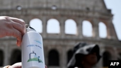 A Civil protection worker shows a water bottle at a help point in front of the Colosseum to help people coping with heat, during a heatwave in Rome on July 18, 2023. 