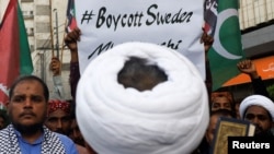 Pakistani Shi'ite Muslim supporters of Majlis-e-Wahdat-e-Muslimeen (MWM) carry a poster, as they listen to the speech during a protest, to denounce the desecration of Koran outside a mosque in the Swedish capital Stockholm, in Karachi, July 2, 2023.