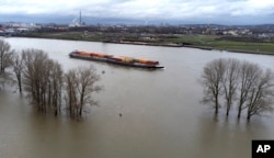 The river Rhine floods as a vessel drives past the city of in Duisburg, Germany, Dec. 29, 2023.
