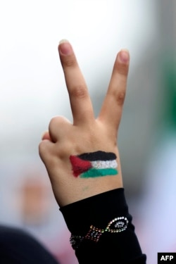 An Iranian woman with a Palestinian flag painted on her hand flashes the victory sign during a rally outside the former US embassy in Tehran, Iran, Nov. 4, 2023.