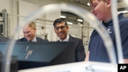 Britain's Prime Minister Rishi Sunak, center, and Grant Shapps, Secretary of State for Energy Security and Net Zero, left, are shown robotics by an apprentice, during a visit to the UK Atomic Energy Authority, Culham Science Centre, in Abingdon, England, March 30, 2023. 