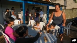 FILE - Venezuelan migrant Natalia Contreras tends to her children as they settle in to have breakfast at a shelter in Rio Branco, Brazil, June 22, 2024.