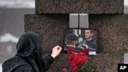 FILE - A woman touches a photo of Alexey Navalny after laying flowers at the Memorial to Victims of Political Repression in St. Petersburg, Russia, on Feb. 17, 2024.