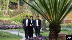 Chinese President Xi Jinping, left, and French President Emmanuel Macron stroll in the garden of the Guandong province governor's residence, in Guangzhou, China, April 7, 2023. (Pool photo via AP)