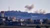 FILE - A picture taken from from the southern Lebanese village of Tayr Harfa, near the border with Israel, shows smoke from rockets fired by Hezbollah billowing near an Israeli outpost on Dec. 15, 2023. 