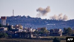 FILE - A picture taken from from the southern Lebanese village of Tayr Harfa, near the border with Israel, shows smoke from rockets fired by Hezbollah billowing near an Israeli outpost on Dec. 15, 2023. 