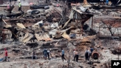 Locals clean up debris of burnt-out houses after forest fires reached their neighborhood in Vina del Mar, Chile, Feb. 4, 2024. 