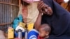 FILE - Hadiiq Abdulle Mohamed holds one of her children as she speaks during an interview with Associated Press at an internally displaced people camp on the outskirts of Mogadishu, Somalia, March 24, 2023. 