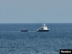 Sebuah kapal militer Korea Selatan menarik kapal Korea Utara yang membawa orang-orang yang diyakini berusaha membelot dari negara tersebut, ke pelabuhan di Yangyang, Korea Selatan, 24 Oktober 2023. (Foto: Yonhap via REUTERS)