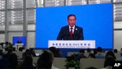 FILE - Journalists in a media center watch Chinese Premier Li Qiang as he speaks at the opening ceremony of the Boao Forum for Asia in Boao in southern China's Hainan province, March 30, 2023. 