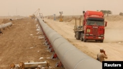 FILE - Workers set up a natural gas pipeline during a dust storm at Iraq's border with Iran, in Basra, southeast of Baghdad, April 12, 2016. 