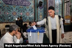 Seorang pria Iran sedang memasukkan surat suara di sebuah TPS di Teheran dalam pilpres untuk memilih pengganti mendiang Presiden Ebrahim Raisi yang meninggal dalam kecelakaan helikopter, Jumat, 28 Juni 2024. (Foto: Majid Asgaripour/WANA via Reuters)