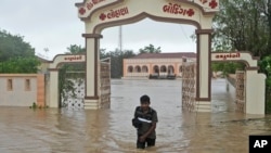 A man wades through flooded street following heavy winds and incessant rains after landfall of cyclone Biparjoy at Mandvi in Kutch district of Western Indian state of Gujarat, June 16, 2023.